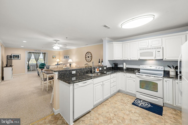 kitchen featuring visible vents, a peninsula, white appliances, white cabinetry, and a sink