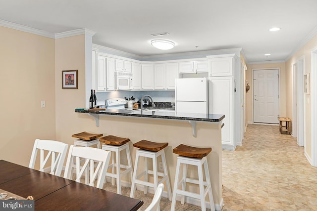 kitchen with a kitchen breakfast bar, white appliances, a peninsula, white cabinets, and crown molding