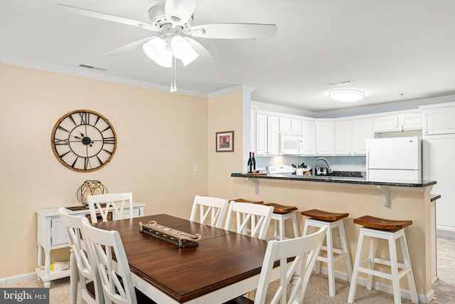 dining space with crown molding, a ceiling fan, visible vents, and baseboards