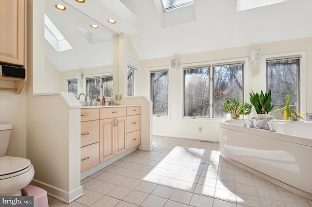 bathroom with tile patterned floors, vaulted ceiling with skylight, toilet, and recessed lighting