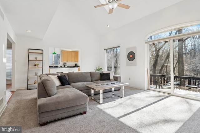 living room with ceiling fan, high vaulted ceiling, baseboards, and light carpet