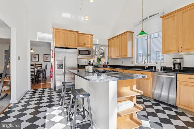 kitchen featuring a breakfast bar area, high vaulted ceiling, a sink, appliances with stainless steel finishes, and dark floors