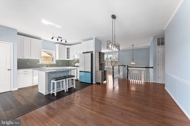 kitchen featuring visible vents, glass insert cabinets, decorative backsplash, dark wood-style floors, and white appliances