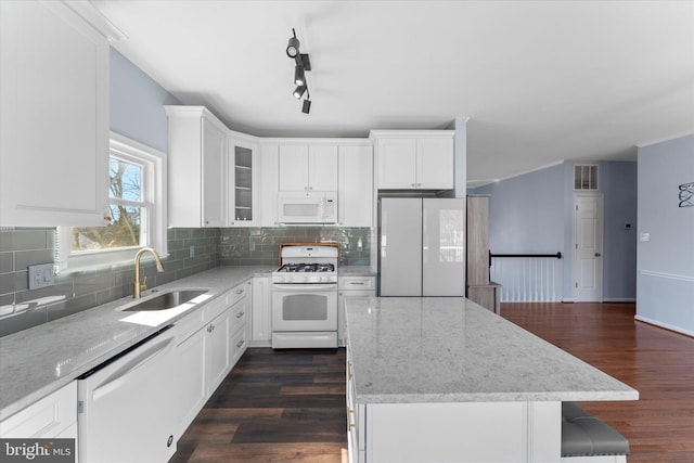 kitchen with visible vents, a sink, a kitchen island, white appliances, and dark wood-style flooring