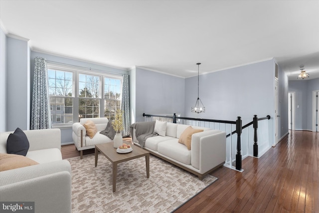 living area featuring baseboards, an inviting chandelier, crown molding, and hardwood / wood-style flooring