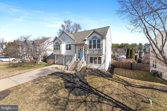 split foyer home with a garage, driveway, a front lawn, and fence