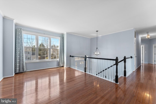 unfurnished room with baseboards, a notable chandelier, hardwood / wood-style floors, and crown molding