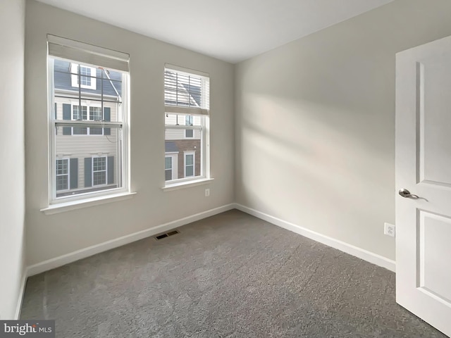 carpeted spare room featuring visible vents and baseboards