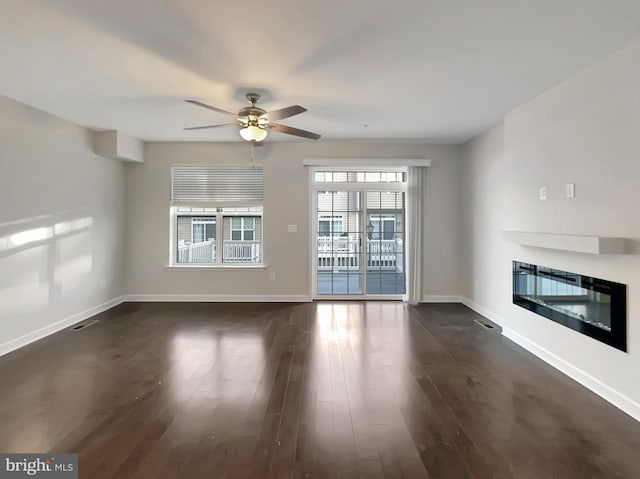 unfurnished living room featuring a ceiling fan, baseboards, visible vents, dark wood-type flooring, and a glass covered fireplace