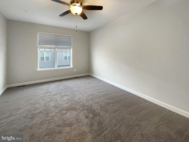 unfurnished room featuring baseboards, a ceiling fan, and dark carpet