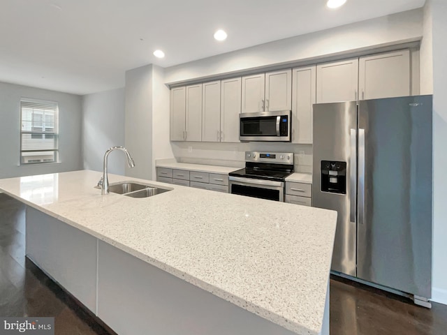 kitchen with light stone countertops, recessed lighting, gray cabinets, appliances with stainless steel finishes, and a sink