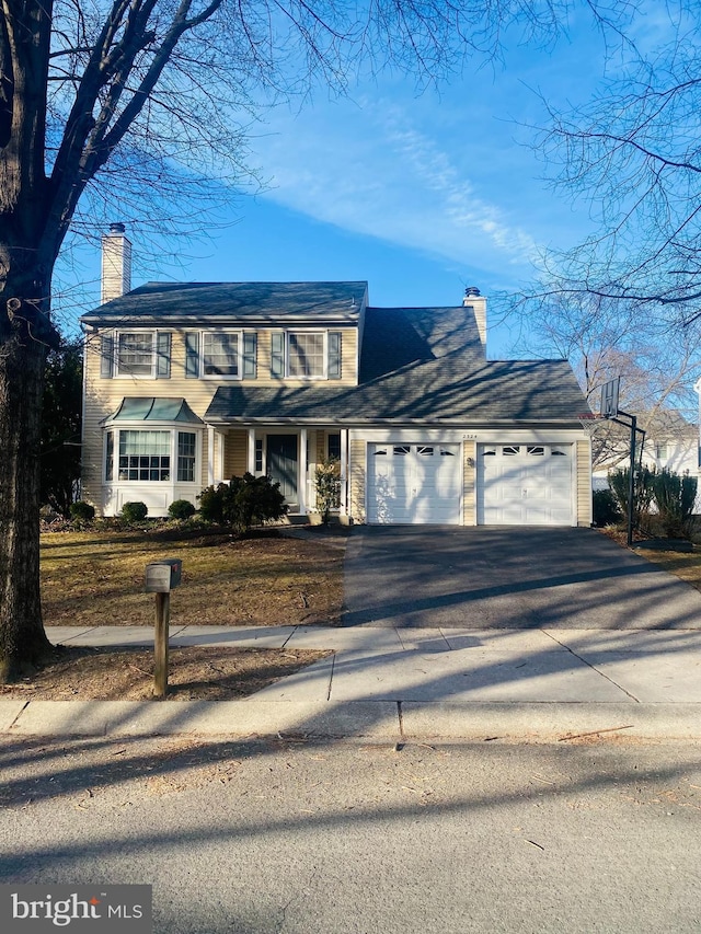 traditional-style home with a garage, driveway, and a chimney