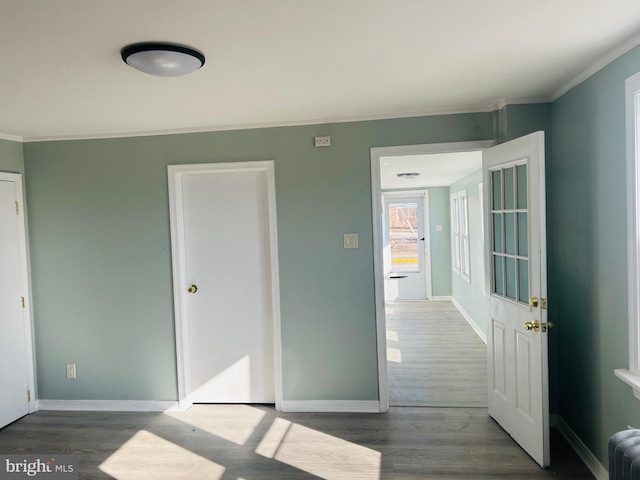 bedroom featuring baseboards, radiator, wood finished floors, and crown molding