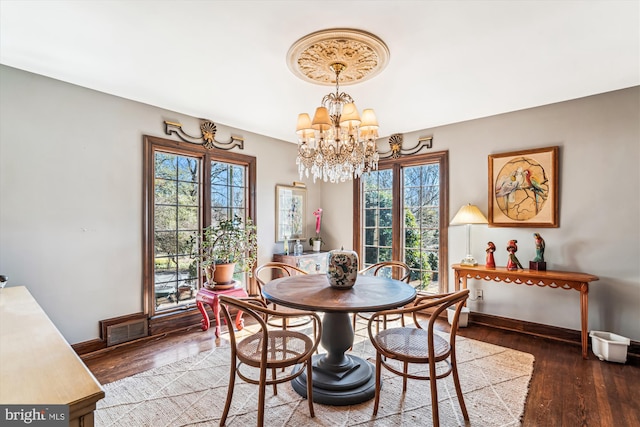 dining area featuring an inviting chandelier, wood finished floors, visible vents, and baseboards