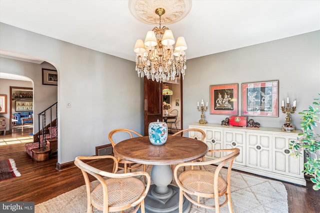 dining area featuring baseboards, a chandelier, stairway, wood finished floors, and arched walkways