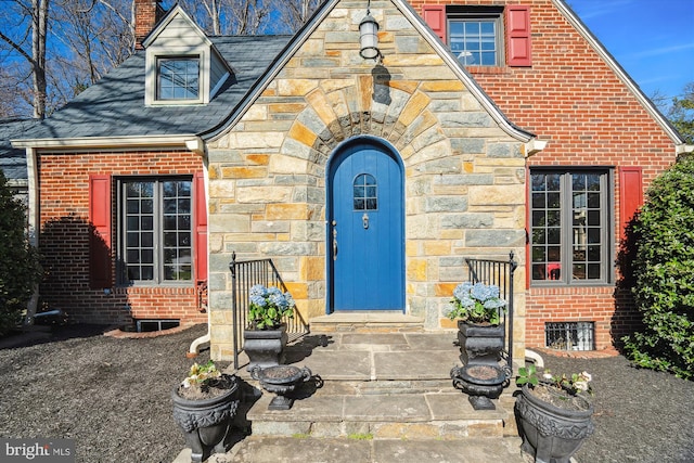 property entrance with brick siding, stone siding, and a chimney