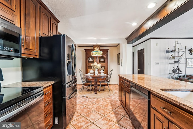 kitchen with recessed lighting, appliances with stainless steel finishes, brown cabinetry, light tile patterned floors, and light stone countertops