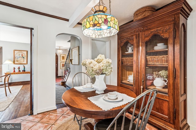 dining space with baseboards, stairway, beam ceiling, light tile patterned floors, and arched walkways