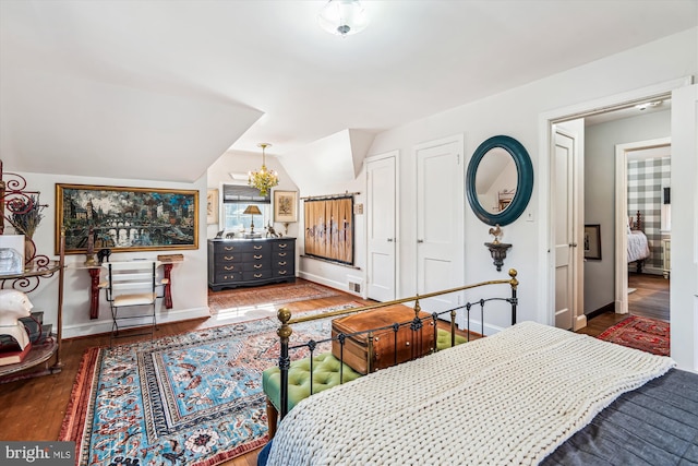 bedroom with baseboards, wood finished floors, and vaulted ceiling