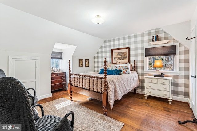 bedroom featuring wallpapered walls, lofted ceiling, baseboards, and hardwood / wood-style floors