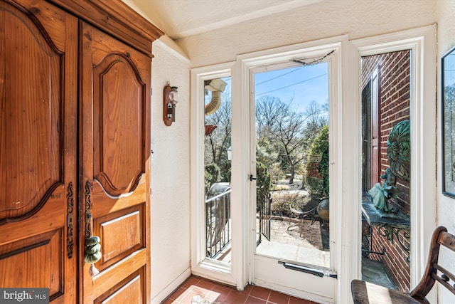 doorway to outside featuring tile patterned floors and a textured wall