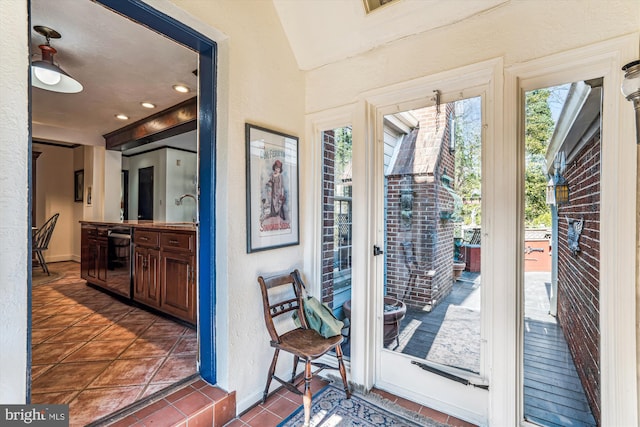 doorway with tile patterned floors, a textured wall, and a sink