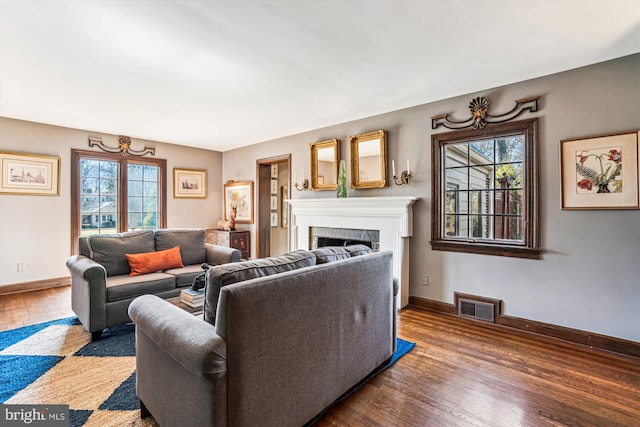 living area with visible vents, baseboards, wood finished floors, and a fireplace