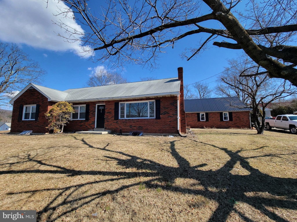 ranch-style home featuring a front yard, brick siding, and a chimney