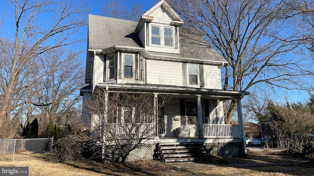 view of front of home with fence, covered porch, and roof with shingles