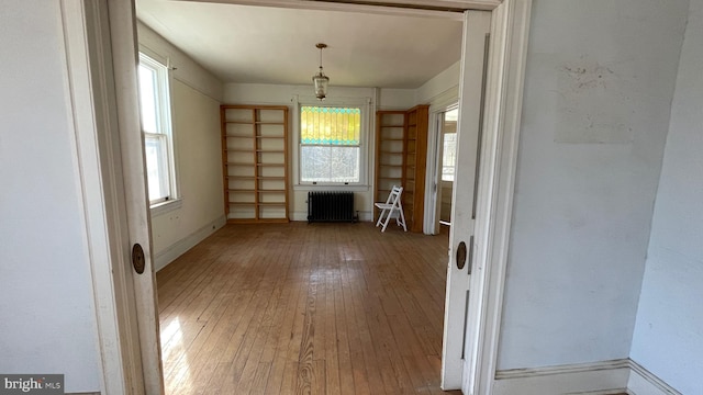 interior space with a wealth of natural light, radiator, baseboards, and hardwood / wood-style floors