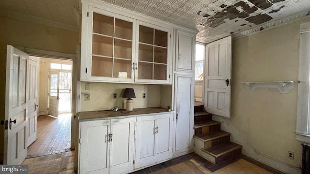 kitchen featuring dark countertops, glass insert cabinets, baseboards, and an ornate ceiling