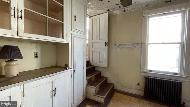 staircase featuring tile patterned flooring, radiator heating unit, baseboards, and an ornate ceiling