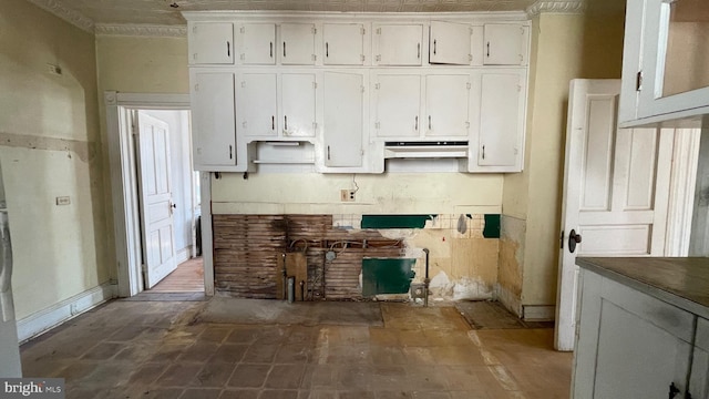 kitchen featuring under cabinet range hood, crown molding, and white cabinetry