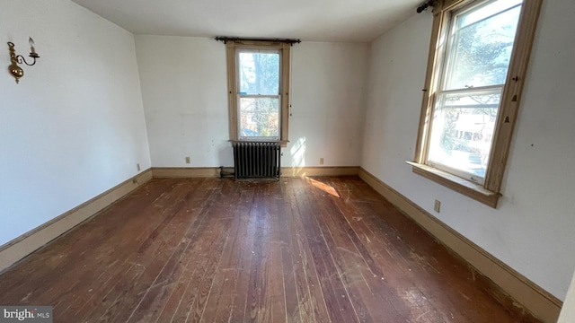 unfurnished room with baseboards, radiator heating unit, and hardwood / wood-style flooring