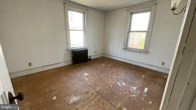 spare room featuring baseboards and radiator