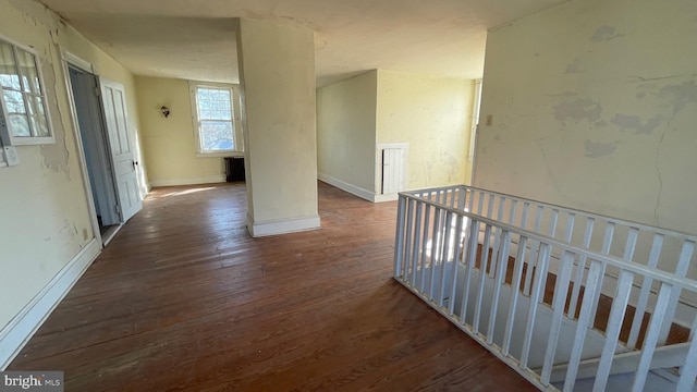 corridor featuring baseboards and hardwood / wood-style floors