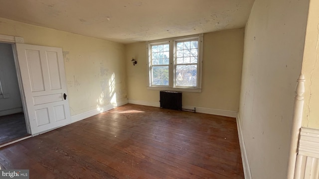 empty room featuring baseboards, hardwood / wood-style floors, and radiator heating unit