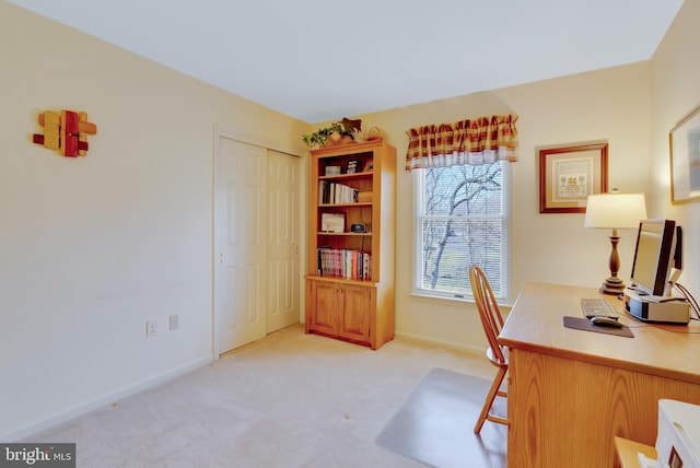 office area featuring baseboards and light carpet