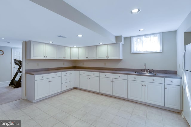 kitchen with visible vents, baseboards, recessed lighting, white cabinets, and a sink