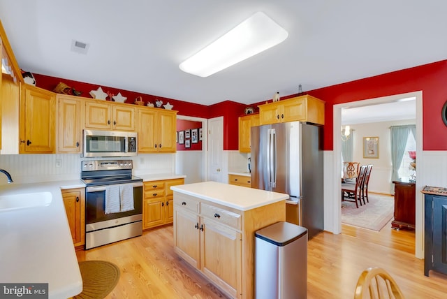 kitchen with appliances with stainless steel finishes, light countertops, light wood-style floors, and a sink