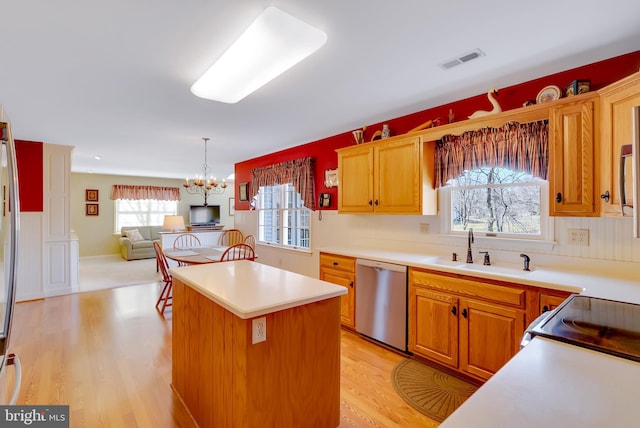 kitchen with visible vents, a kitchen island, a sink, light wood-style floors, and dishwasher