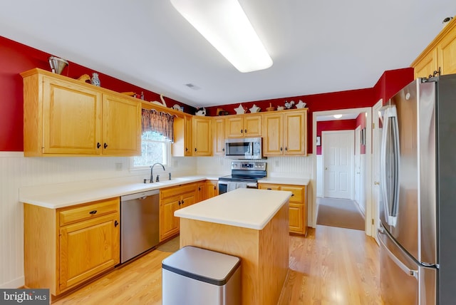 kitchen with a sink, appliances with stainless steel finishes, light countertops, and light wood finished floors