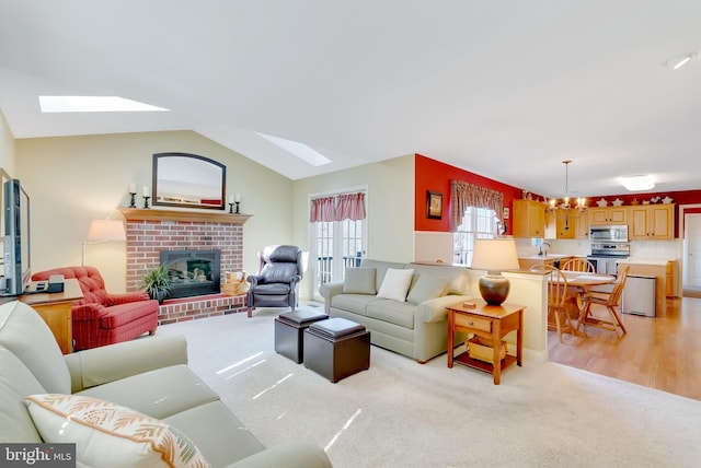 living area with an inviting chandelier, lofted ceiling, a brick fireplace, and light colored carpet