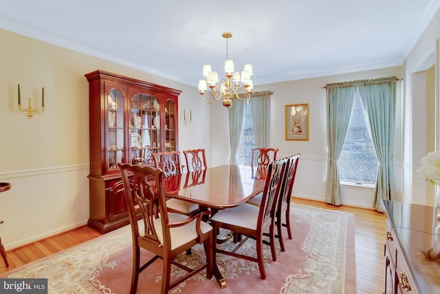 dining area featuring an inviting chandelier, crown molding, light wood-style floors, and baseboards