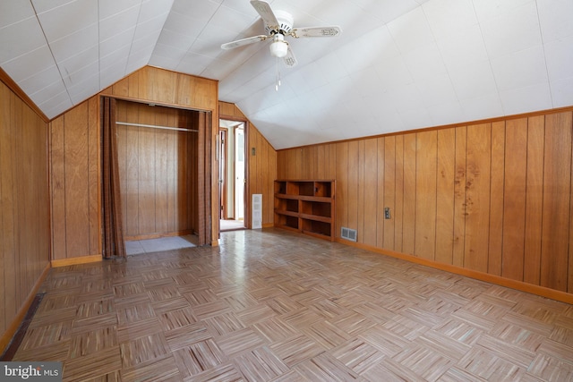 bonus room featuring visible vents, baseboards, wood walls, vaulted ceiling, and a ceiling fan