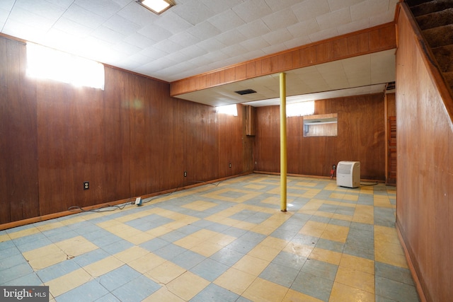 below grade area with tile patterned floors, wooden walls, baseboards, and visible vents