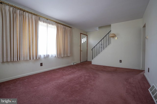 unfurnished living room featuring stairs, baseboards, visible vents, and carpet floors