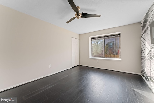 unfurnished bedroom with ceiling fan, a closet, baseboards, and dark wood finished floors