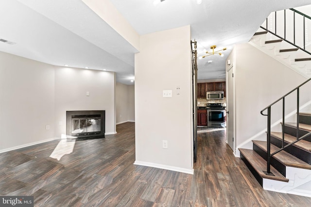 interior space with visible vents, stairway, dark wood-style flooring, and a glass covered fireplace