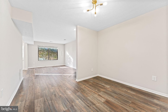 unfurnished room featuring a notable chandelier, baseboards, and wood finished floors